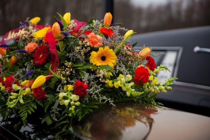 funeral-casket-and-flowers-next-to-hearse_t20_6lGr8Y