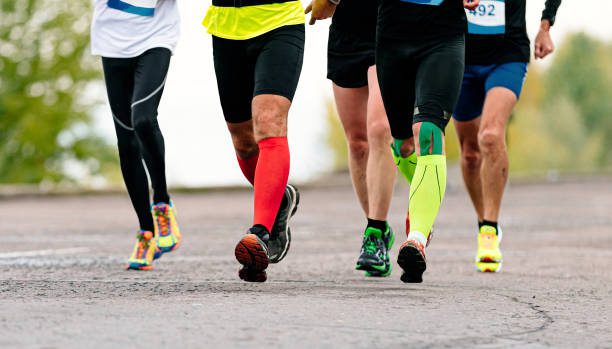 legs male runners in compression socks and kinesio tape run marathon